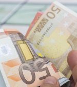 Close-up view of unrecognizable man counting money. Horizontal composition. Studio shot. Image developed from RAW format.