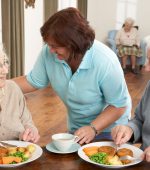 Senior Couple Being Served Meal By Carer