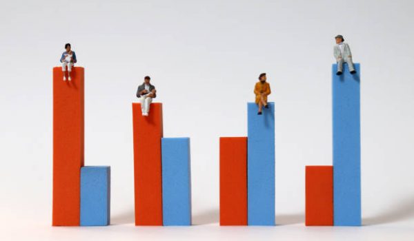 Miniature people sitting on a bar graph.