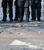 Stones and bricks litter the road as police riot squad move forward