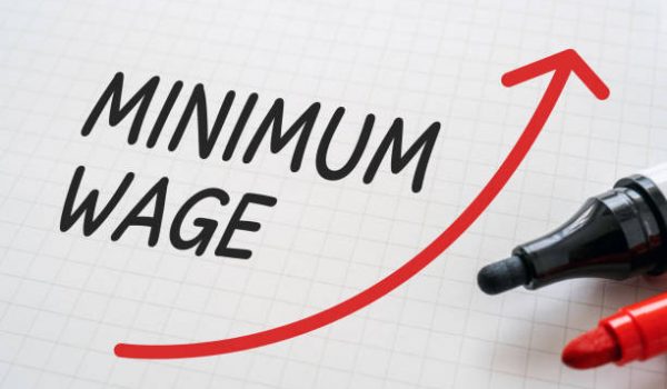 White paper written "MINIMUM WAGE" with markers.