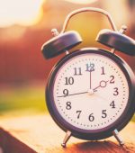 Daylight savings time. Retro clock outdoors with warm glow