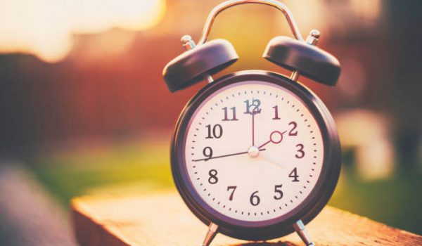 Daylight savings time. Retro clock outdoors with warm glow