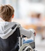 young-boy-in-wheelchair-wearing-gray-hoodie-gazing-thoughtfully-in-a-bright-modern-space-symbolizing-resilience-and-determination-in-life-photo